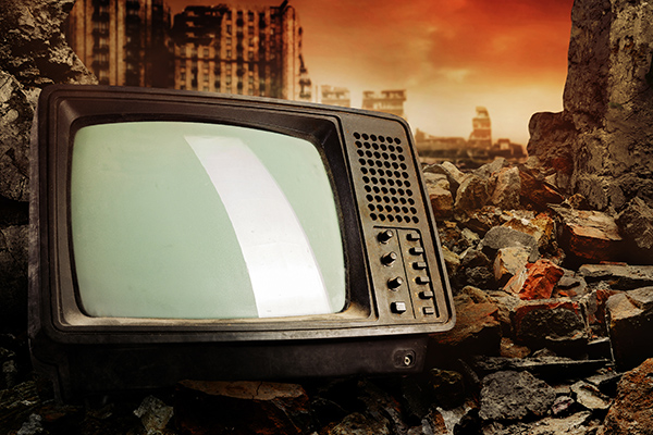 Image: Old fashioned tv set laying on pile of bricks on ruined city wasteland