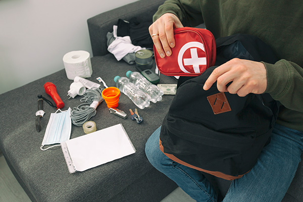 Image: Young man packing the bag with documents, water, food, first aid kit and other items needed to survive 