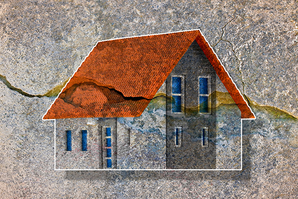 Image: Deep crack in old brick wall with damaged plaster and colored house model.