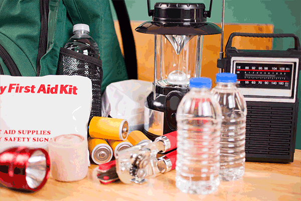 Image: Contents of an earthquake emergency kit: first aid items, flashlight, batteries, water, lamp, radio, can opener