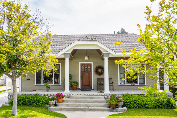 Image: Front of white raised foundation house with red door