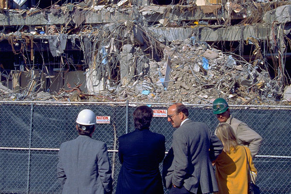 Image: Experts survey office building with one side entirely collapsed